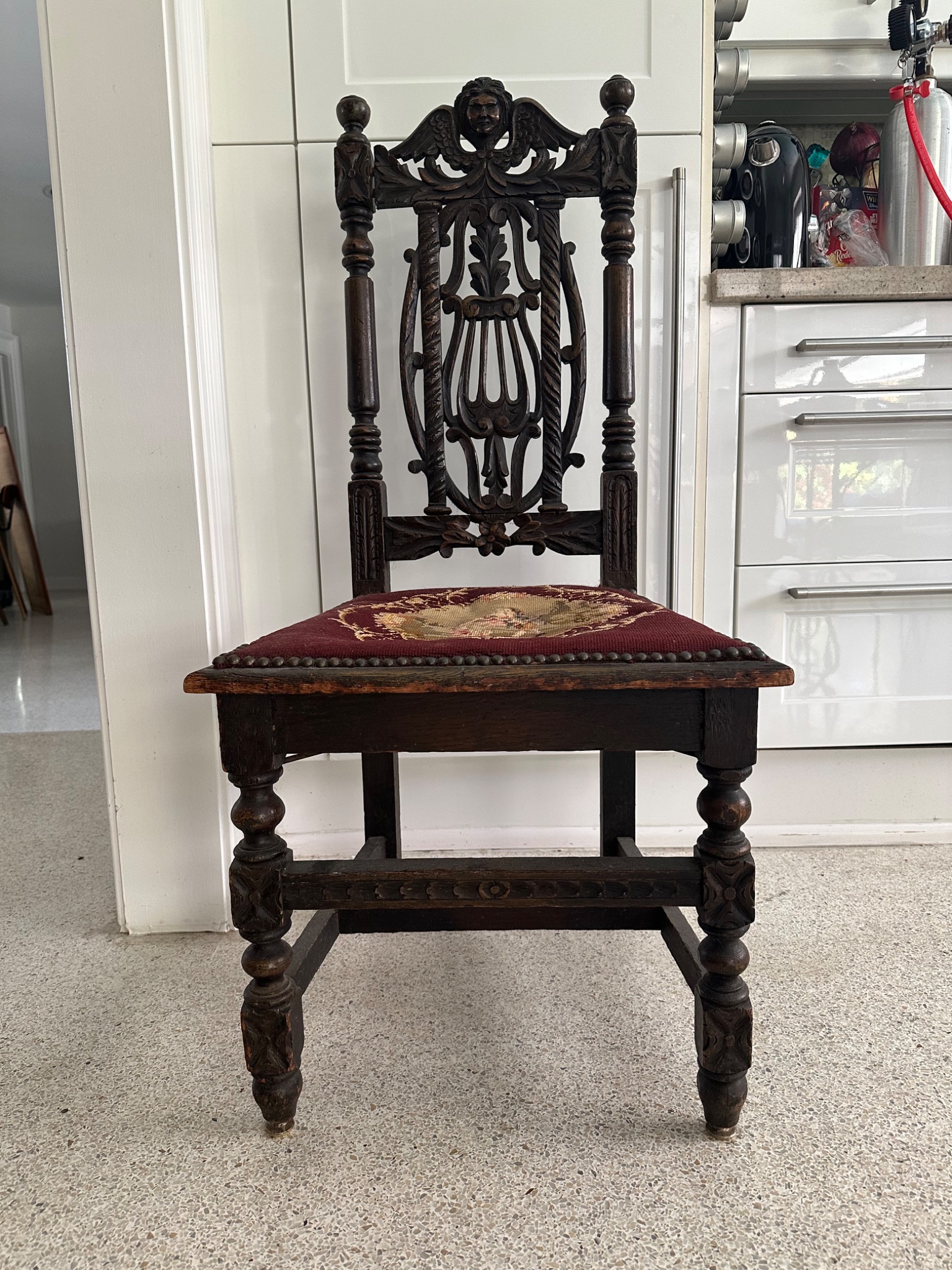 Carved oak side chair with upholstered seat and figural crest