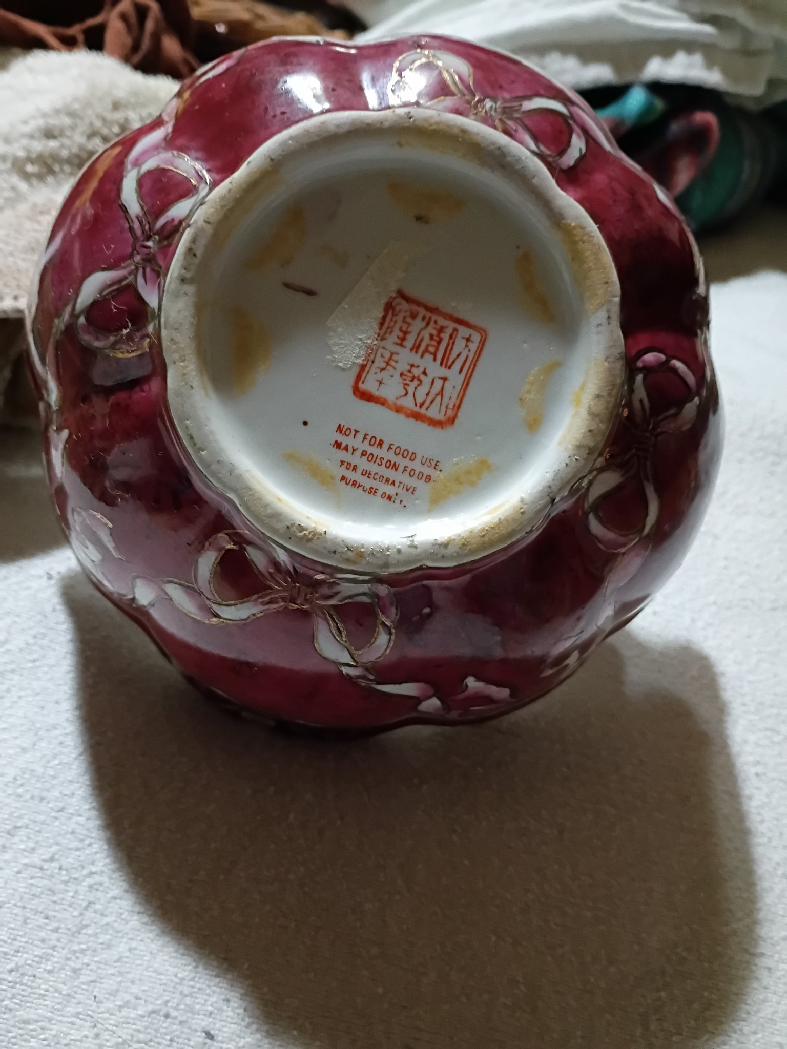 Decorative porcelain vase or jar with red glaze and gilt bow motif