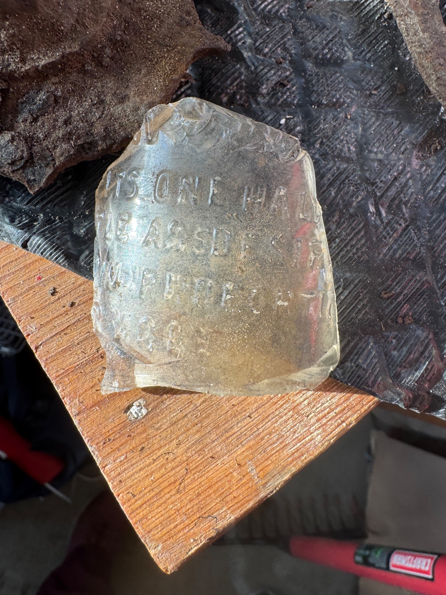 Embossed glass bottle fragment (likely medicine or utility bottle shard)