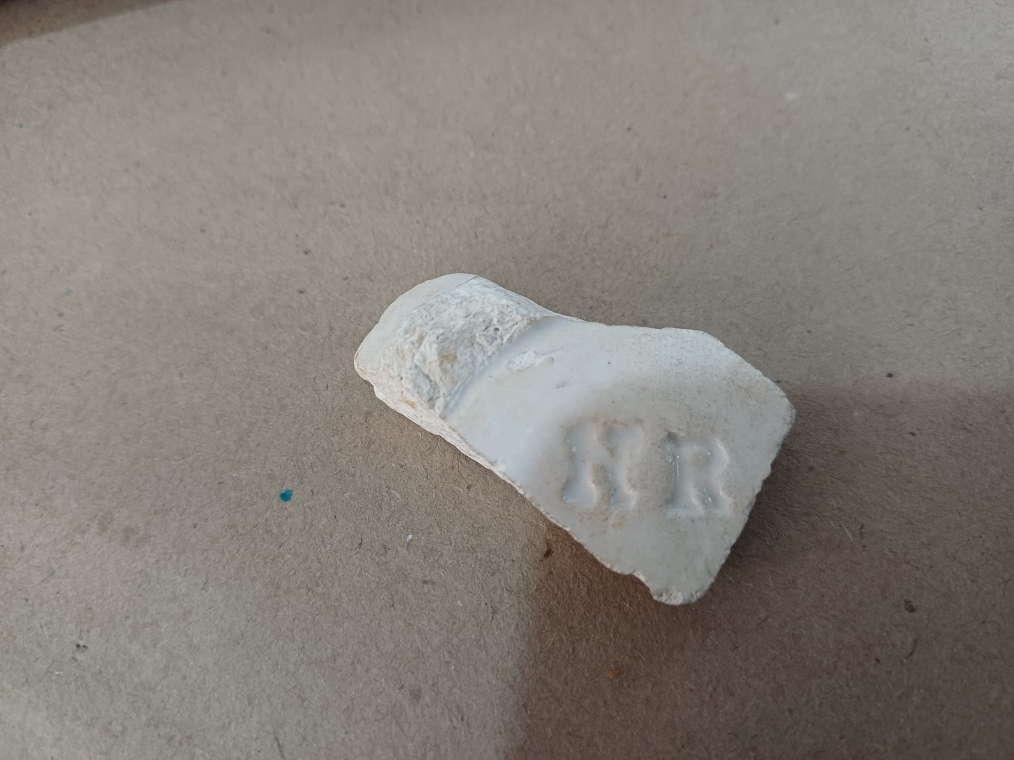 Fragment of a white glazed ceramic or porcelain object with impressed maker's mark